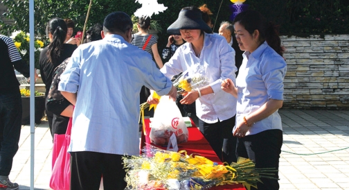 工作人员正在向参与祭祀的市民派送鲜花 。