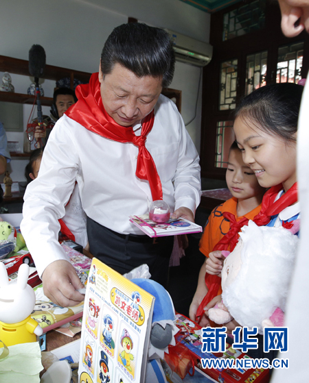 这是习近平与学生一起为帮助民族地区生活困难的小朋友进行爱心义卖活动。新华社记者 鞠鹏 摄 